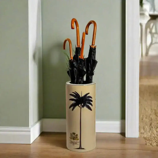 Beige umbrella stand with black palm tree design holding four black umbrellas on a white background
