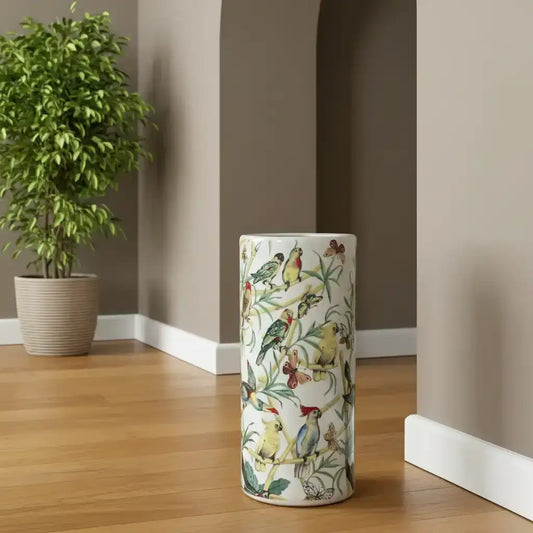 Decorative umbrella stand with bird pattern on a wooden floor next to a plant.