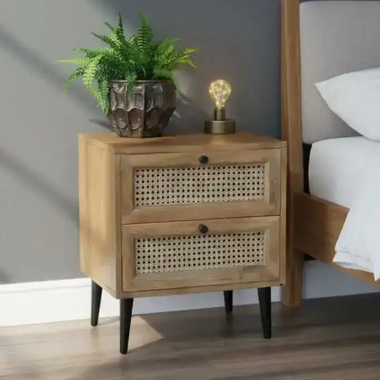 Wooden nightstand with two drawers, a potted plant, and a lamp in a bedroom setting.