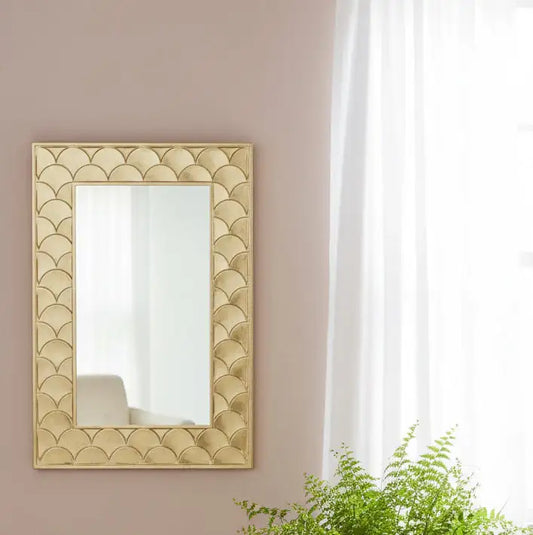 Decorative mirror with geometric pattern on a wall with a potted plant below.