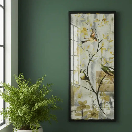 Framed artwork of birds on branches with flowers on a green wall next to a potted plant.