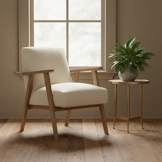 Beige armchair with wooden frame and legs, placed next to a small round table with a plant in a room with large windows.