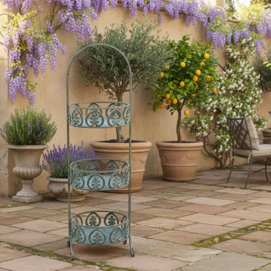 Decorative metal plant stand in a garden setting with potted plants and flowers.