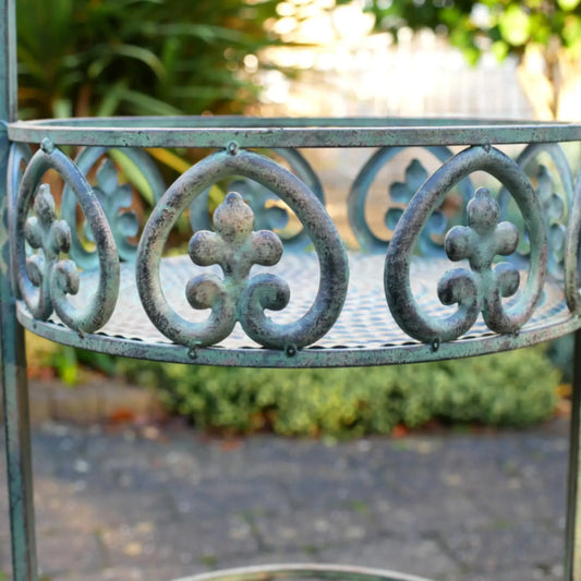 Decorative metal garden bench with intricate designs in a garden setting