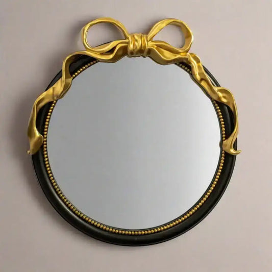 Round mirror with gold bow frame on a beige background