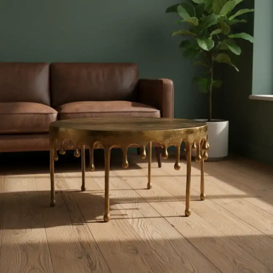 Gold coffee table in a living room with a brown sofa and a plant.