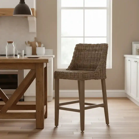 Brown wicker bar stool in a kitchen setting with wooden table and white cabinets.