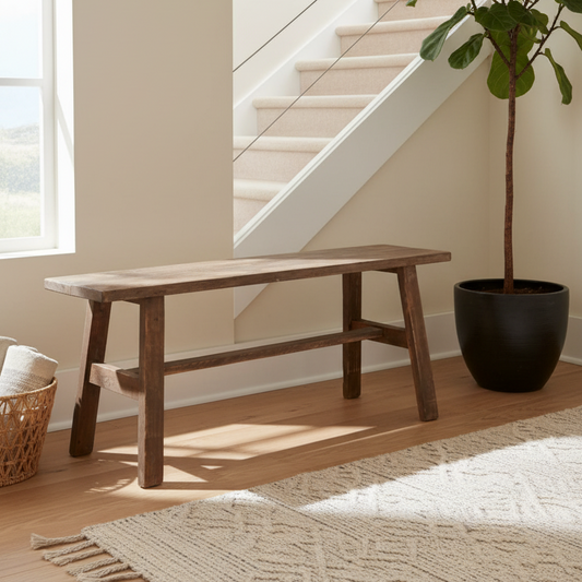 Wooden bench in a room with a plant and staircase in the background