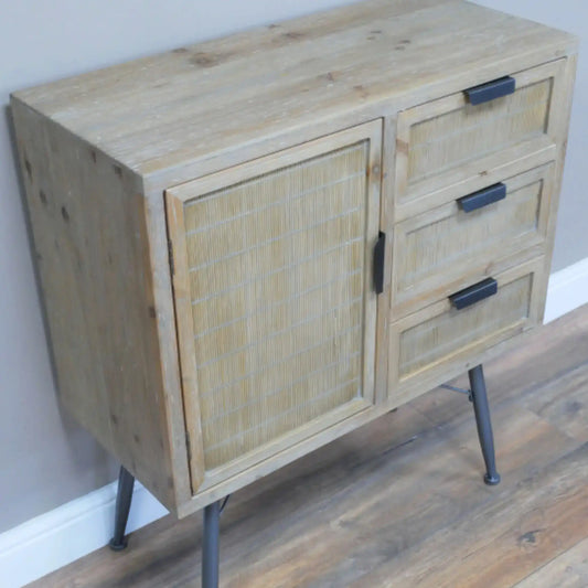 Wooden cabinet with rattan door and metal legs on a wooden floor.