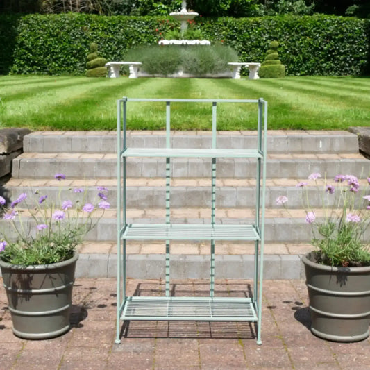Metal garden shelf with plants on a patio area in front of a fountain.