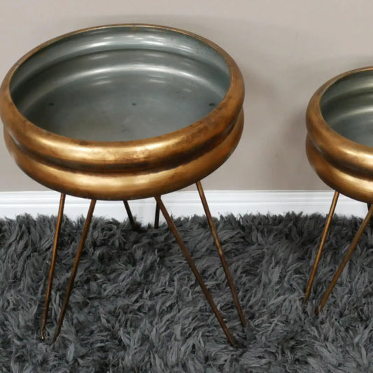 Two metallic side tables with bronze bases and gray tops on a dark gray rug.