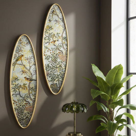 Two oval wall art pieces with nature-themed designs on a brown wall, next to a plant and small lamp.