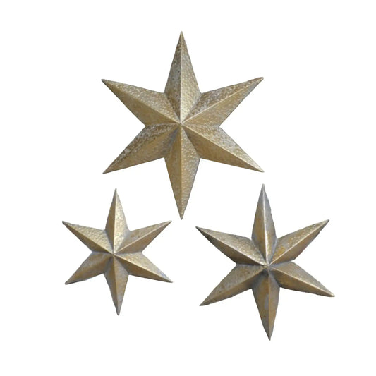 Three gold star-shaped wall decorations on a brick wall.