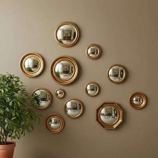 Gold wall mirrors of various sizes on a beige wall with a plant to the left.