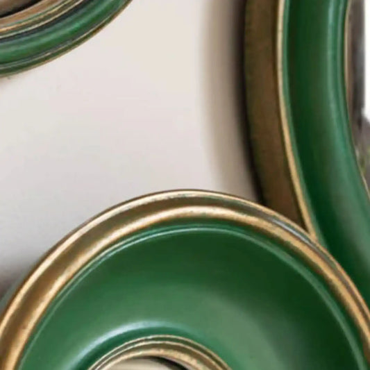 Close-up of green ceramic bowls with gold rims on a white background