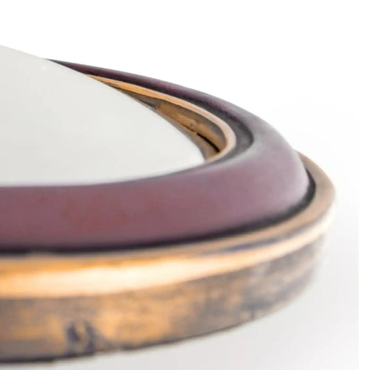 Close-up of a metallic ring with a white object inside on a light background