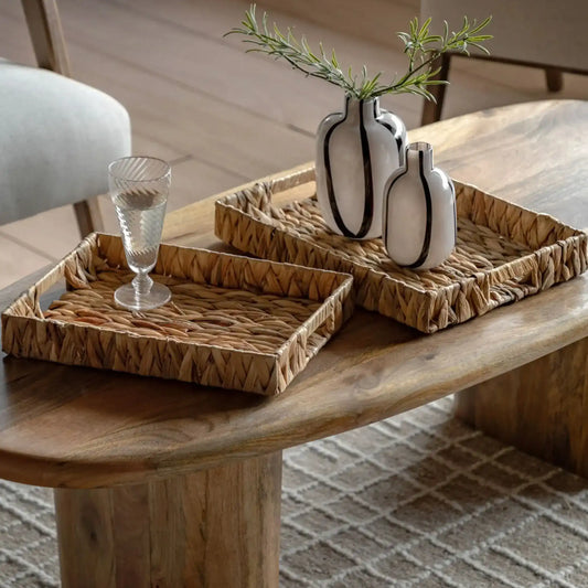Decorative setting with wicker trays and vases on a wooden table.