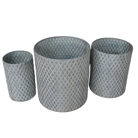 Three textured metal planters of different sizes on a wooden surface with a neutral background.
