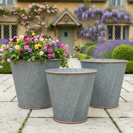Three decorative planters with flowers in front of a house with floral decorations.