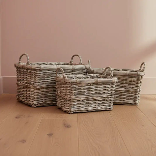 Three wicker baskets of different sizes on a wooden floor with a pink wall background