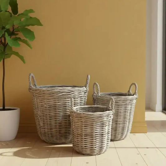 Three wicker baskets of different sizes on a wooden floor with a plant against a yellow wall.