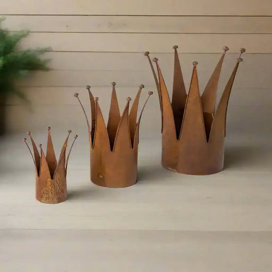 Three rusted metal crowns of different sizes on a white background