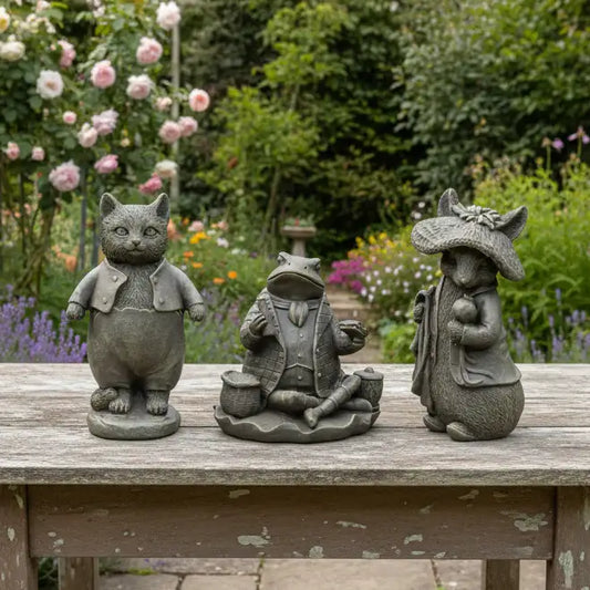 Three stone statues of a cat, frog, and mouse on a wooden bench with a garden background.