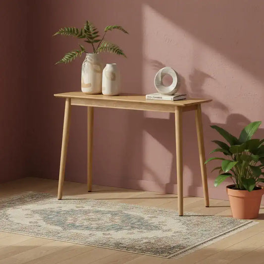 Wooden console table with decorative items against a pink wall