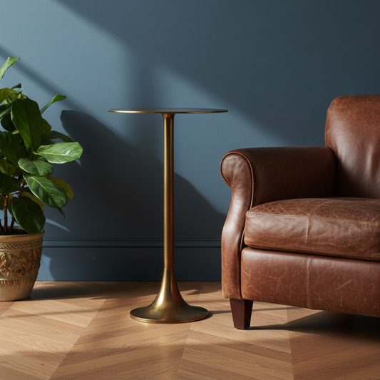 Brown leather armchair and gold side table against a blue wall with a plant on a wooden floor.