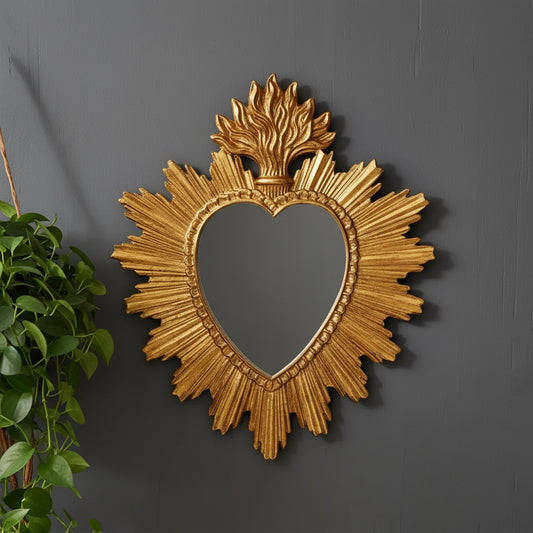 Decorative gold mirror with heart shape and sunburst design on a white background