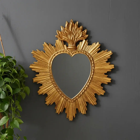 Decorative gold mirror with heart shape and sunburst design on a white background