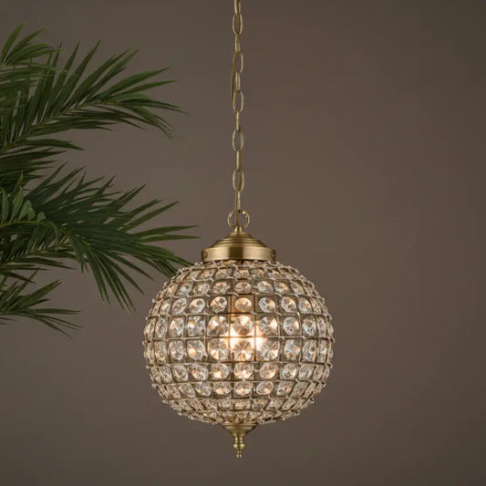 Decorative spherical lamp with crystals hanging against a neutral background