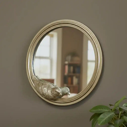Round mirror with gold frame on a brick wall