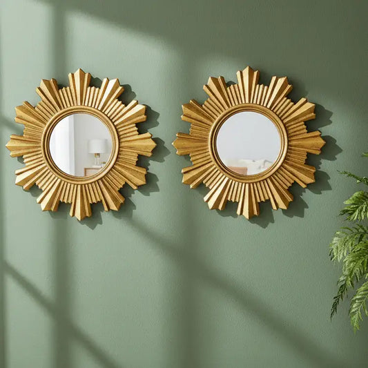 Two gold sunburst mirrors on a green wall with a plant to the right.