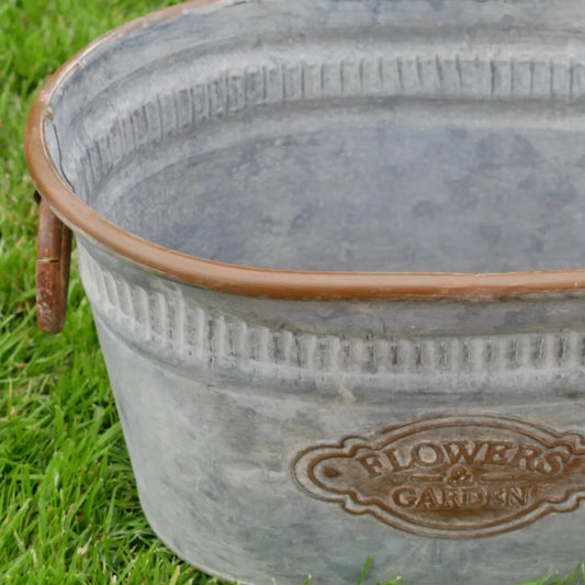Metal bucket with 'Flower Garden' branding on grass