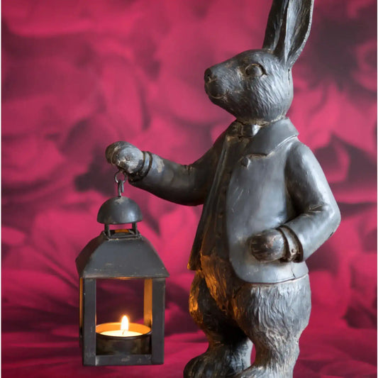 Statue of a rabbit holding a lantern against a red background