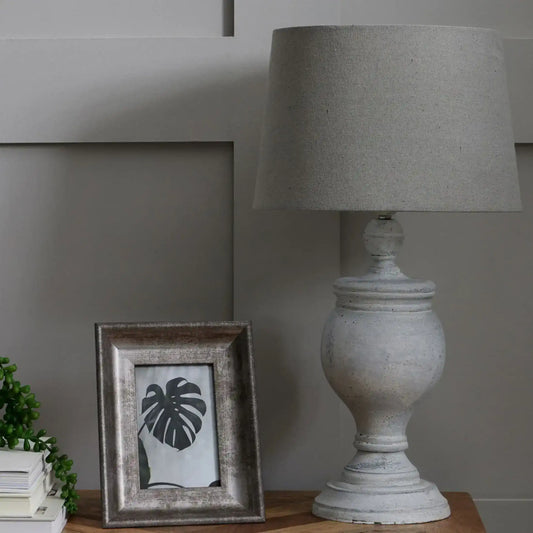 Decorative lamp and framed picture on a wooden surface with a neutral background