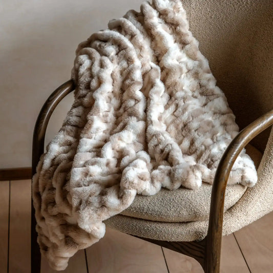 Beige textured blanket draped over a chair in a warm-toned room.
