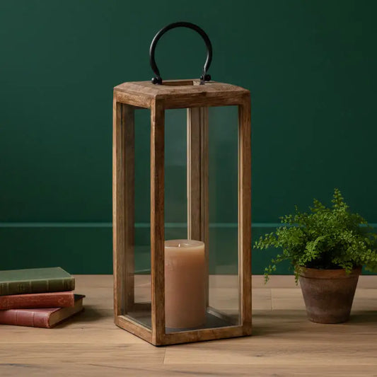 Wooden lantern with a candle on a wooden surface against a green wall.