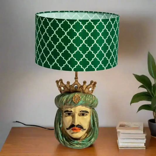 Decorative lamp with a green patterned shade on a wooden surface.
