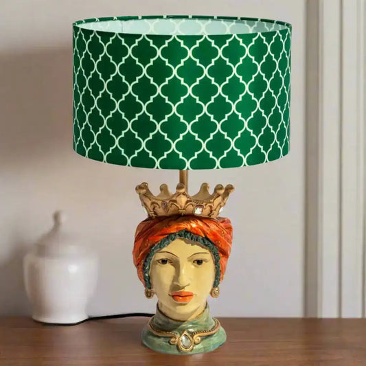 Decorative lamp with a green patterned shade on a wooden surface.