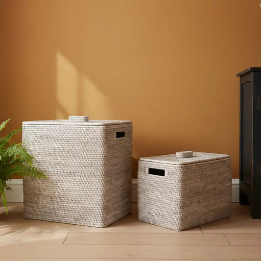 Two woven storage baskets on a wooden floor against an orange wall.