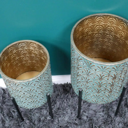 Two decorative pots with gold and teal patterns on a textured surface.