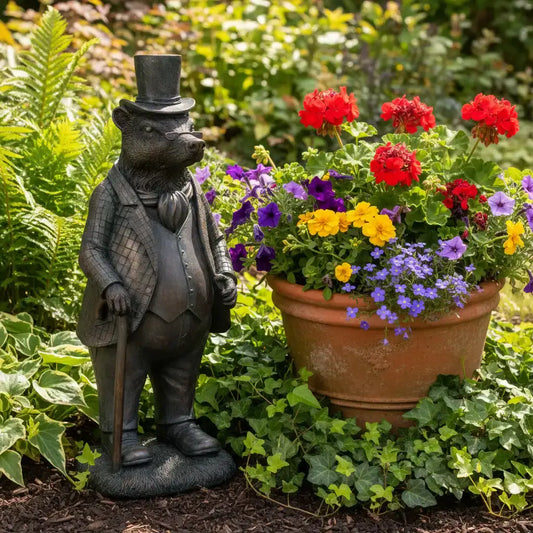 Statue of a bear in a suit next to a potted plant with flowers in a garden setting