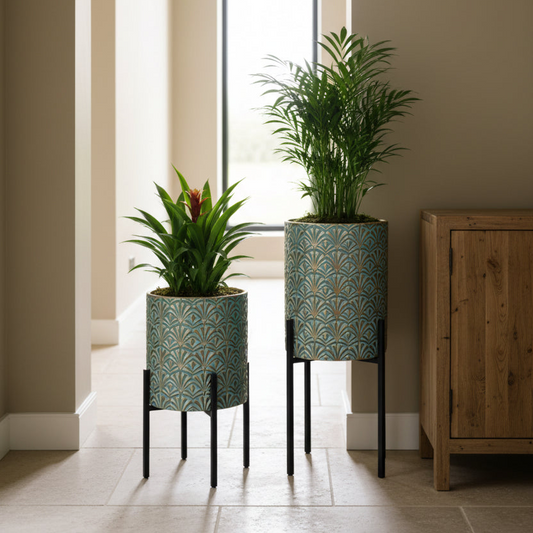 Two potted plants in decorative stands with a wooden cabinet in the background.