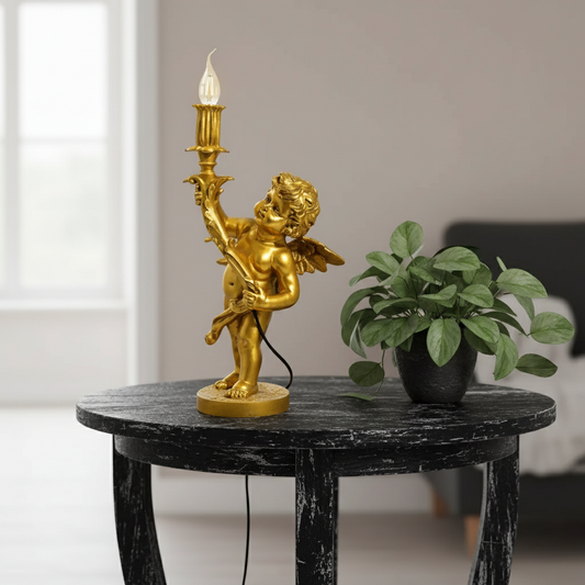 Gold angel lamp on a black marble table with a plant in the background