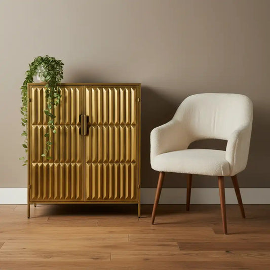 Gold cabinet with textured design next to a white chair on a wooden floor.