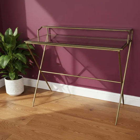 Glass console table with gold metal frame on a neutral background