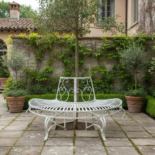 White metal garden bench in a stone-walled courtyard with greenery