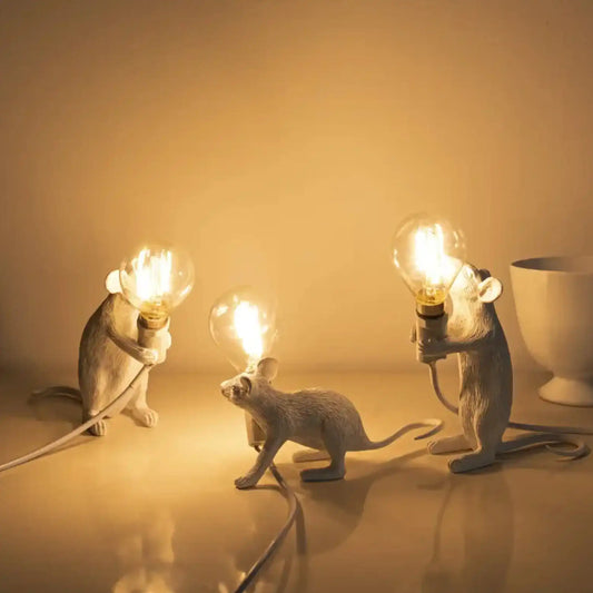 Three mouse-shaped lamps with light bulbs on a warm-toned background